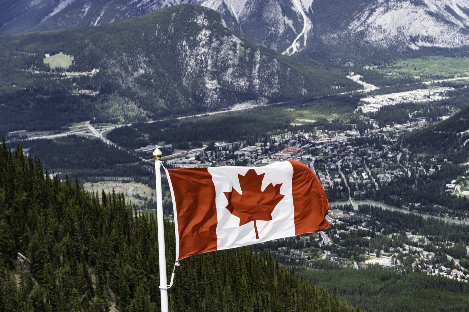 Canadian flag over mountains and forest